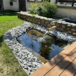 Création d'un aménagement complet avec bassin pour plantes et poissons sur différents niveaux, rives en galets, terrasse bois.